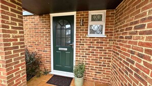 A brick house with a green door, a small window with a decorative grille, and a potted plant on the porch. - Binfield: Spacious Spectacular Five Bedroom House (Binfield)