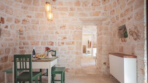 A stone-walled room with a dining table, chairs, and a radiator. - TD I Pagliericci - Enjoy Trulli with Pool (Monopoli)