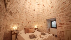 A stone-walled bedroom with a bed, nightstands, and a window. - TD I Pagliericci - Enjoy Trulli with Pool (Monopoli)