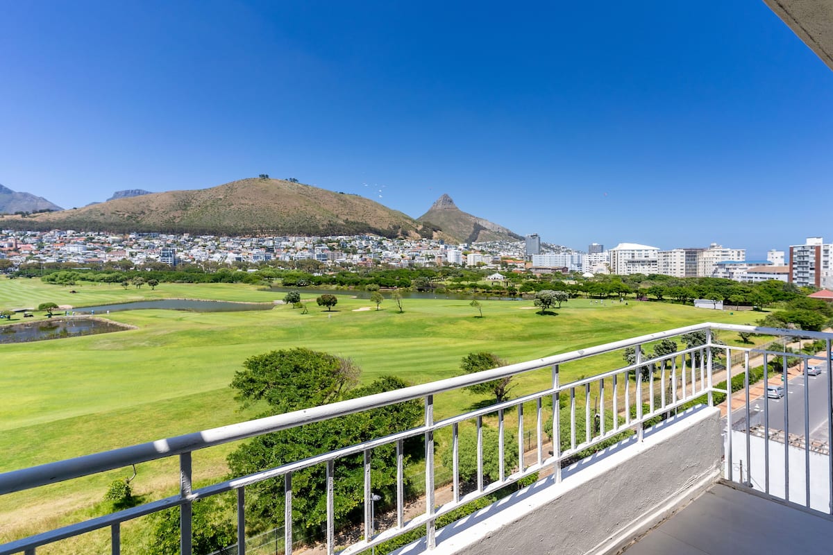 Un balcon offrant une vue sur le paysage urbain, une colline et un terrain de golf.