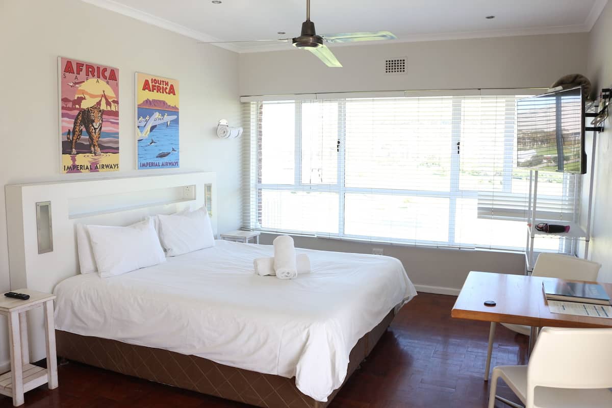 Une chambre d’hôtel avec un grand lit, un bureau et une fenêtre avec des stores.