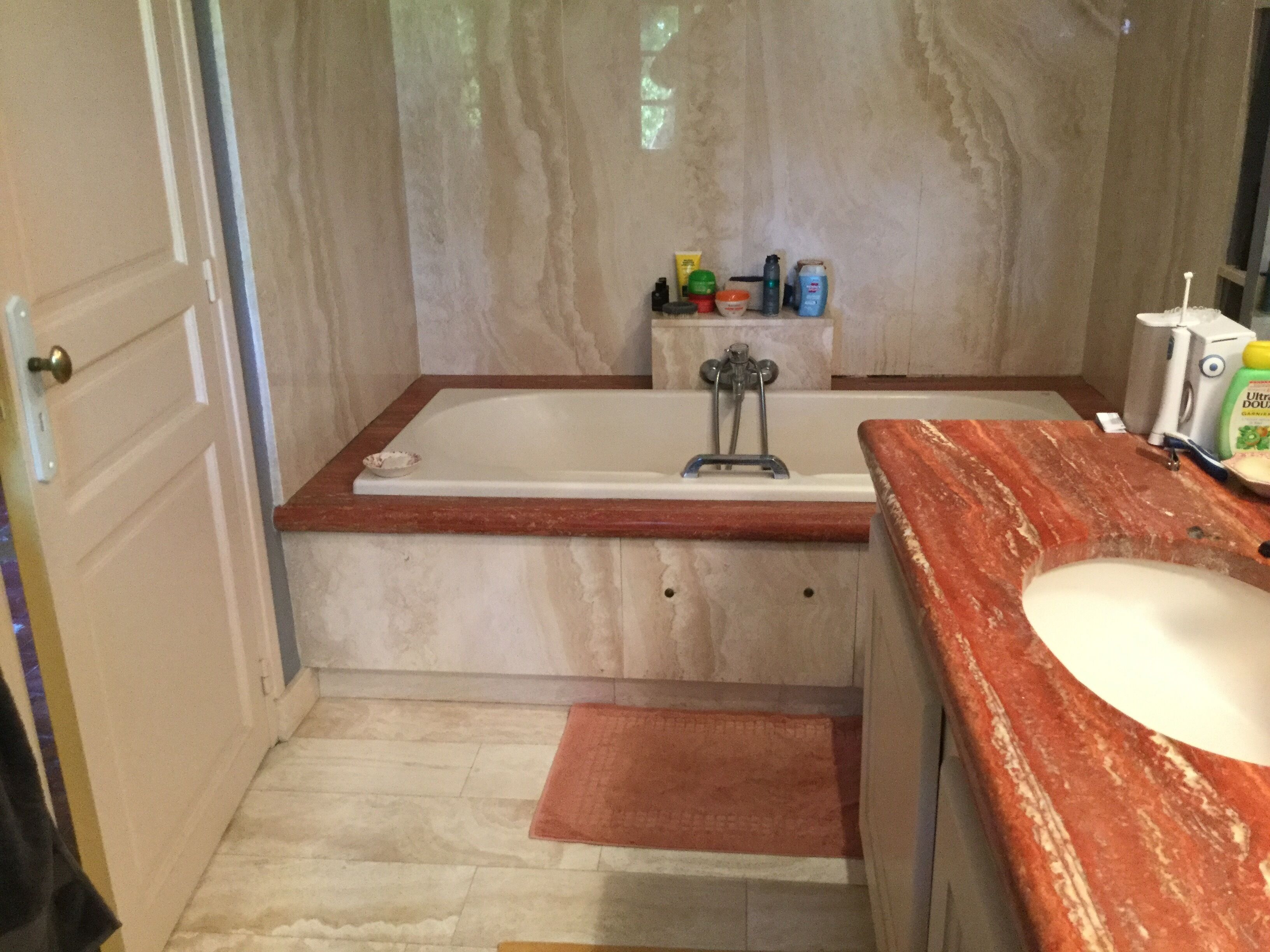 Une salle de bain avec une baignoire, un lavabo et des articles de toilette posés sur le comptoir.