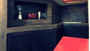 Eine Küche mit dunklen Holzschränken, einem roten Schrank über der Spüle und einem roten Tisch.