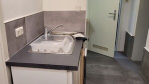 A compact kitchen with a black countertop, a sink, and a built-in dishwasher. - Villa Souterrain, W-lan, Büro (Leverkusen)