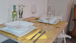 A dining table set with white plates, a wine bottle, and a vase with white flowers. - Villa Souterrain, W-lan, Büro (Leverkusen)