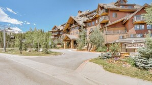 Una cabaña con varios balcones, una entrada central y un letrero que dice "Crystal Peak Lodge".