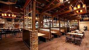 Un restaurante con vigas de madera, pilares de piedra y varias zonas de estar, incluyendo cabinas y mesas.