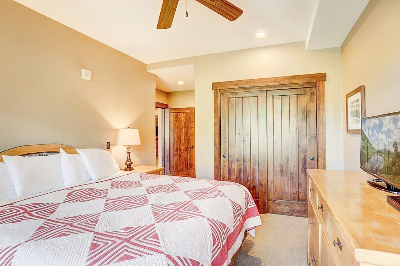 A bedroom with a bed, wooden wardrobe, and a dresser.