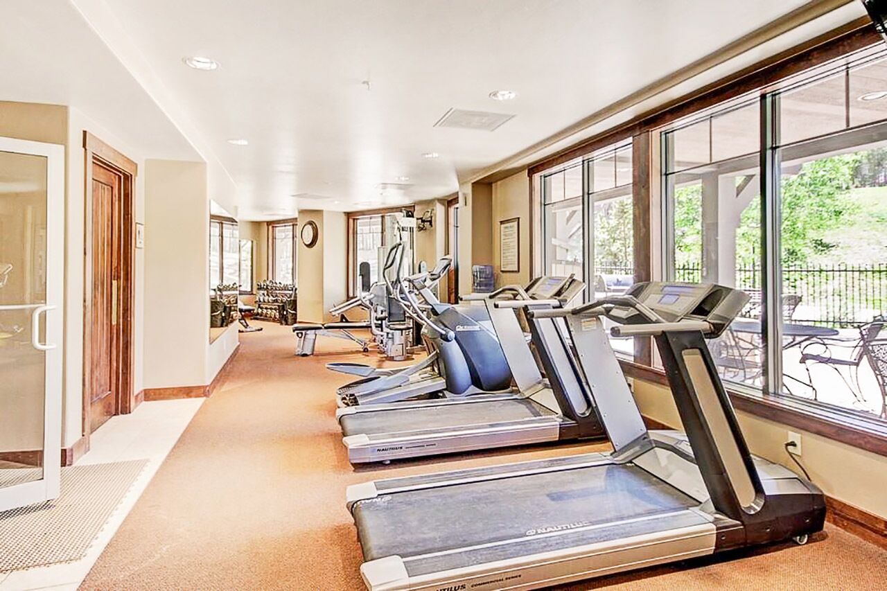Et fitnesscenter med løbebånd, motionscykler og et spejl.