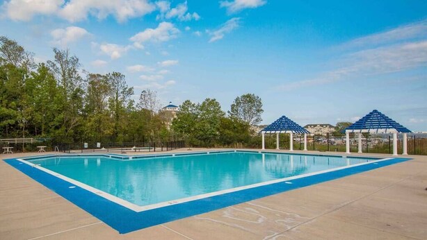 Una piscina con borde azul, rodeada por un área pavimentada y árboles.