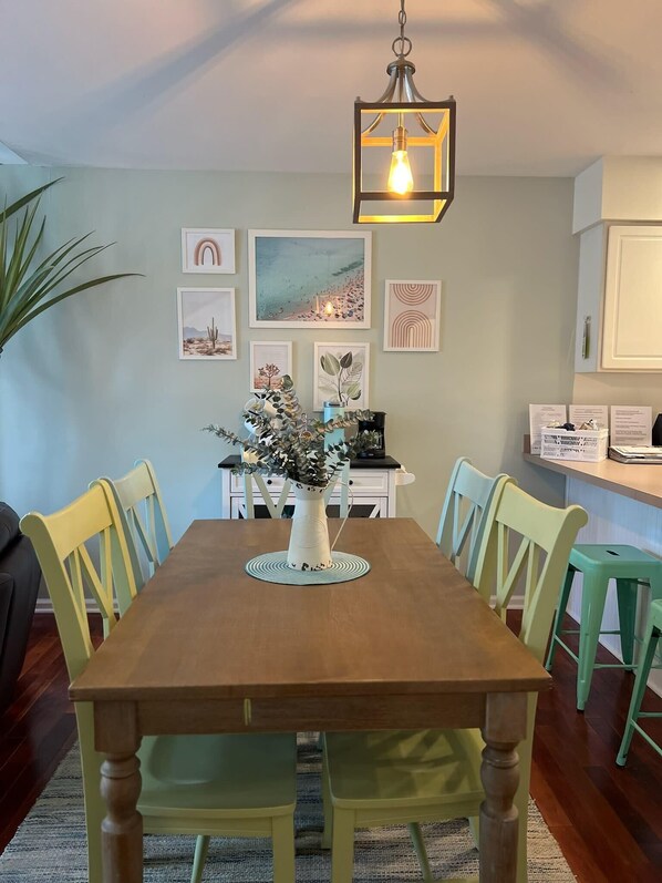 A dining area with a wooden table, green chairs, a vase with flowers, and artwork on the wall. - Tranquil Waters, OceanPines, 3 br, Dog Friendly (Ocean Pines)