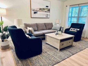 A living room with a sofa, armchairs, a coffee table, and a rug.