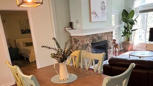 Spiseområde med et træbord, fire stole, en vase med planter og en hængende lampe.