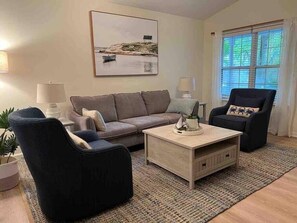 Un salon comprenant un canapé, deux fauteuils, une table basse et un tableau accroché au mur.