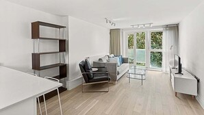 Una sala de estar moderna con un sofá, una mesita de centro, una estantería y un mueble para la televisión.