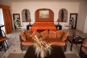 Relax in this stylish room featuring a central bed, sofa, and two chairs, plus a small table for your convenience.