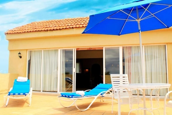 Relax in style with comfortable lounge chairs and a shaded table under a patio umbrella.