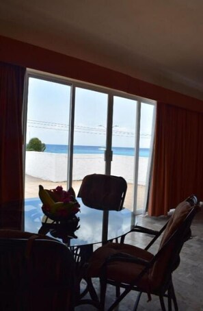 Enjoy a room with a sliding glass door leading to a balcony overlooking the sea and sandy shore.