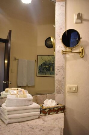 Bathroom features a marble countertop, a round mirror, and a towel rack.