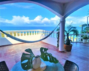 Ein Balkon mit Blick auf das Meer, einer Hängematte und Topfpflanzen.