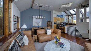 A spacious living area with a large window, a kitchen, and a dining area. - Vail Ski Home next to National Forest (Vail)