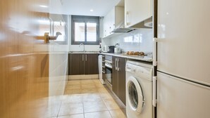A modern kitchen with stainless steel appliances, a built-in oven, and a washing machine. - Inside Barcelona Apartments Princep (Barcelona)
