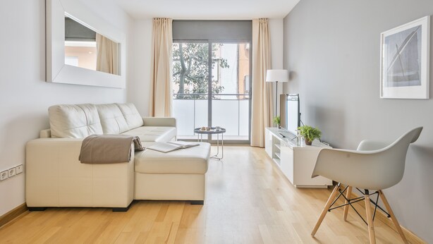 A modern living room with a sofa, a dining area with a chair, a small table, and a view of the outside. - Inside Barcelona Apartments Princep (Barcelona)