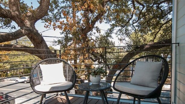 A balcony with two black wicker chairs and a small round table with a potted plant. - NEW Hip & Stylish House 30 steps from South Congress
 (Austin)