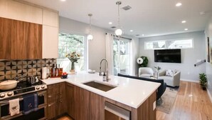 A modern kitchen with wooden cabinets, a white countertop, and a built-in oven. - NEW Hip & Stylish House 30 steps from South Congress
 (Austin)