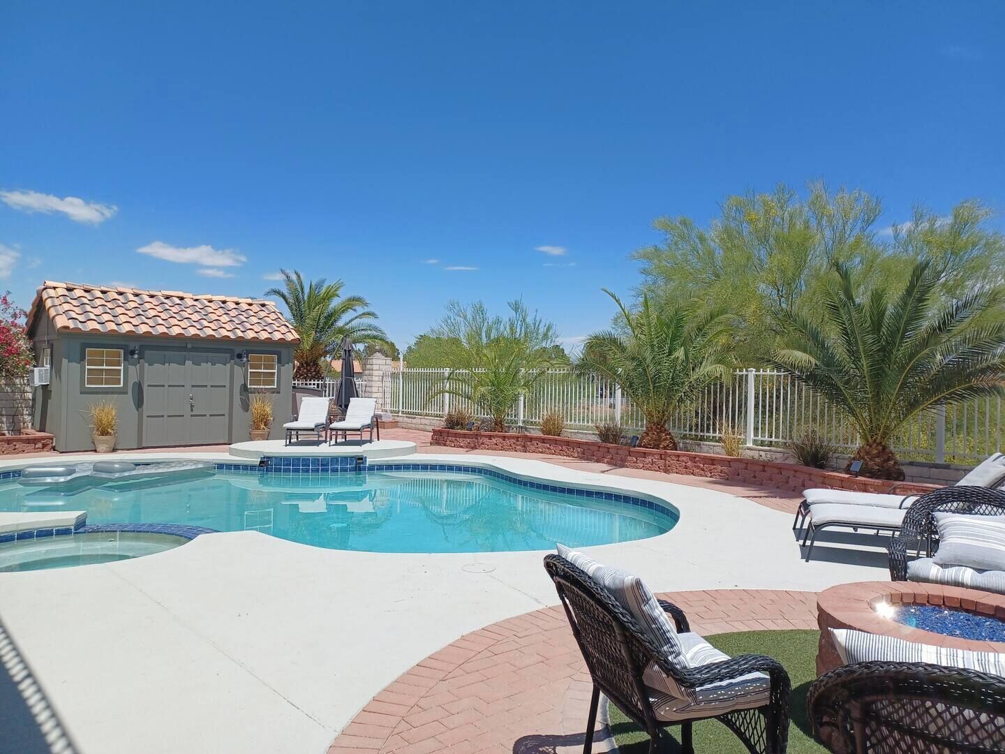 A swimming pool with lounge chairs and a small building with a tiled roof.