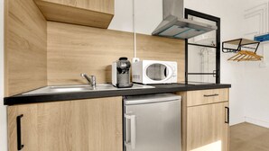 Eine moderne Küche mit Holzschränken, einem Edelstahlkühlschrank, einer Kaffeemaschine und einer Mikrowelle.