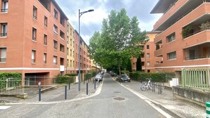 A street with red brick apartment buildings, a no parking sign, and a bicycle parked on the sidewalk.