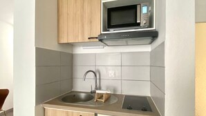 A compact kitchen with a built-in microwave, a sink, and a small refrigerator.