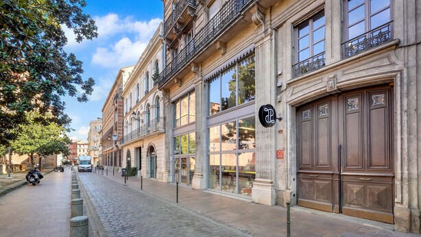 Eine Kopfsteinpflasterstraße gesäumt von historischen Gebäuden mit großen Fenstern und verzierten Balkonen.