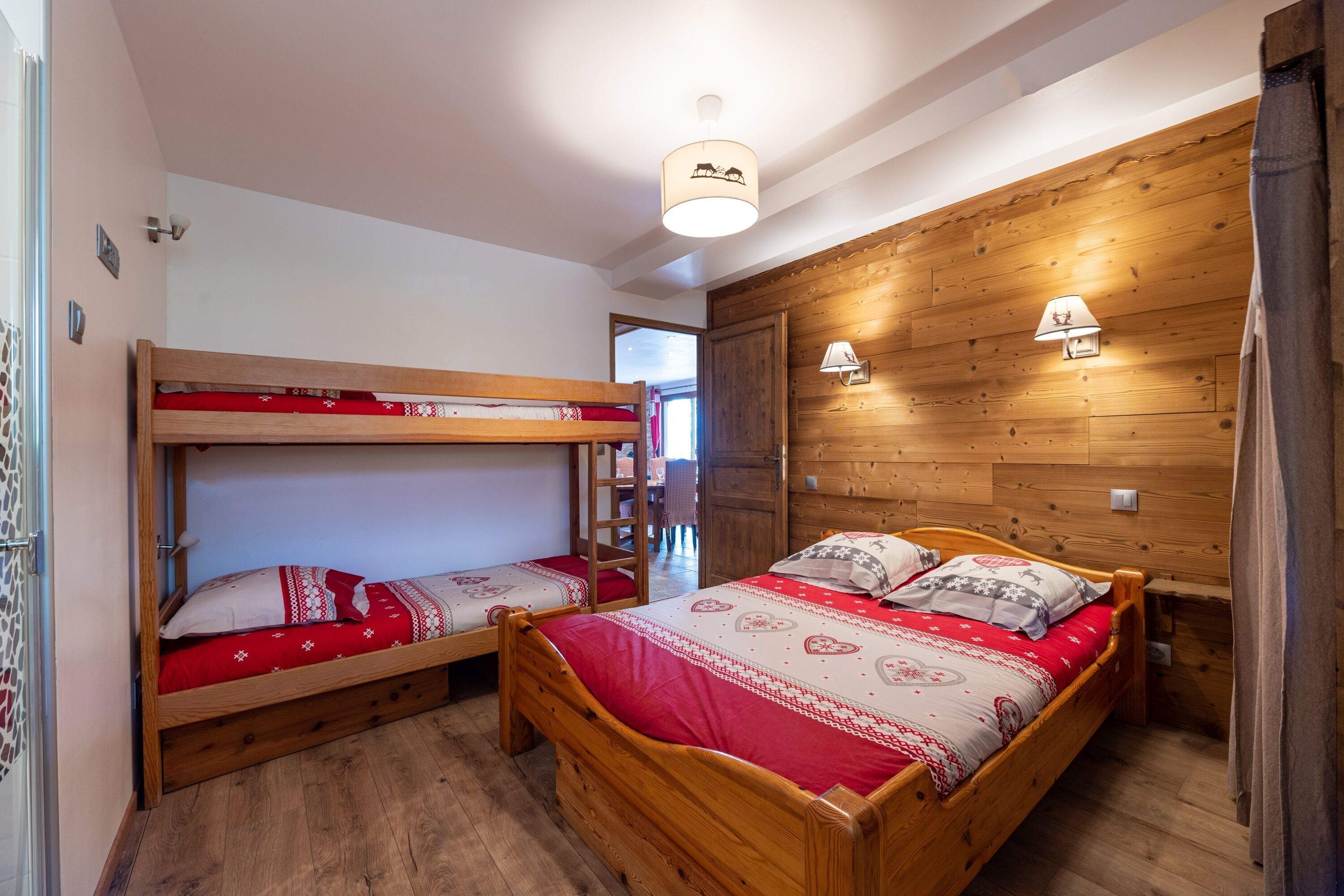 A room with two wooden bunk beds, a wooden wall panel, and a ceiling light fixture.