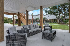 Relax in a spacious outdoor area with a central seating area and wooden beams, surrounded by a well-maintained lawn and trees.