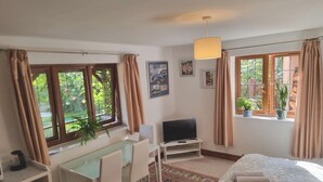 A room with a bed, a desk with a chair, a television, and a window with curtains. - Sunnyside Cottage - Rural 2-bedroom apartment (Bristol)