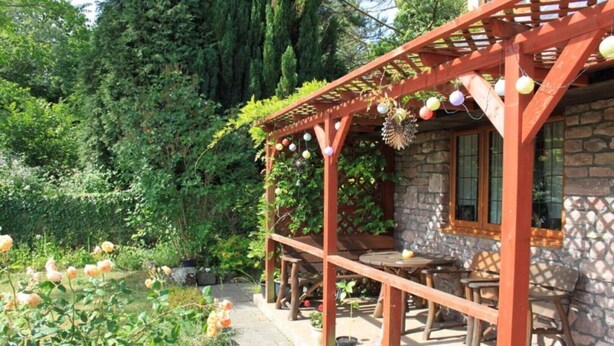 A stone building with a wooden pergola and outdoor seating area. - Sunnyside Cottage - Rural 2-bedroom apartment (Bristol)