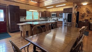 Une cuisine spacieuse avec des meubles en bois, un grand îlot central et un coin repas équipé de chaises.