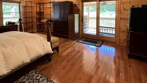 Une chambre dans une cabane en bois, avec un lit, une commode et une grande fenêtre.