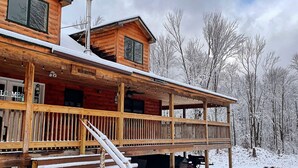 Une cabane en bois dotée d’un porche couvert et d’un escalier menant à l’entrée.