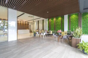 A modern interior with a wooden ceiling, a green wall, and a reception desk. - Capital O 1200 Salem Riverside Hotel (Da Nang)
