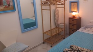 A bedroom with a bed, a wardrobe, a mirror, a lamp, and a wall with framed pictures. - Habitación Privada con Cuarto de Baño (Cádiz)