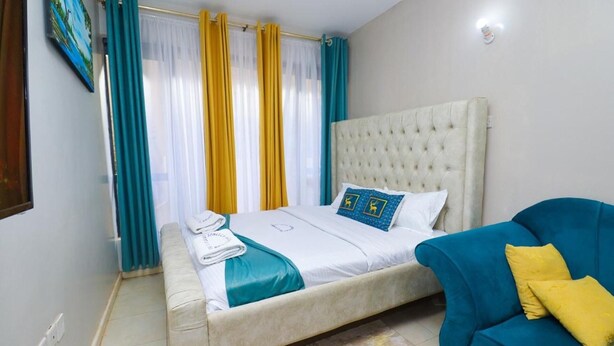 A bedroom with a bed, a blue sofa, and curtains. - Songeza Furnished Accomoda-super Studio,embakasi (Nairobi)