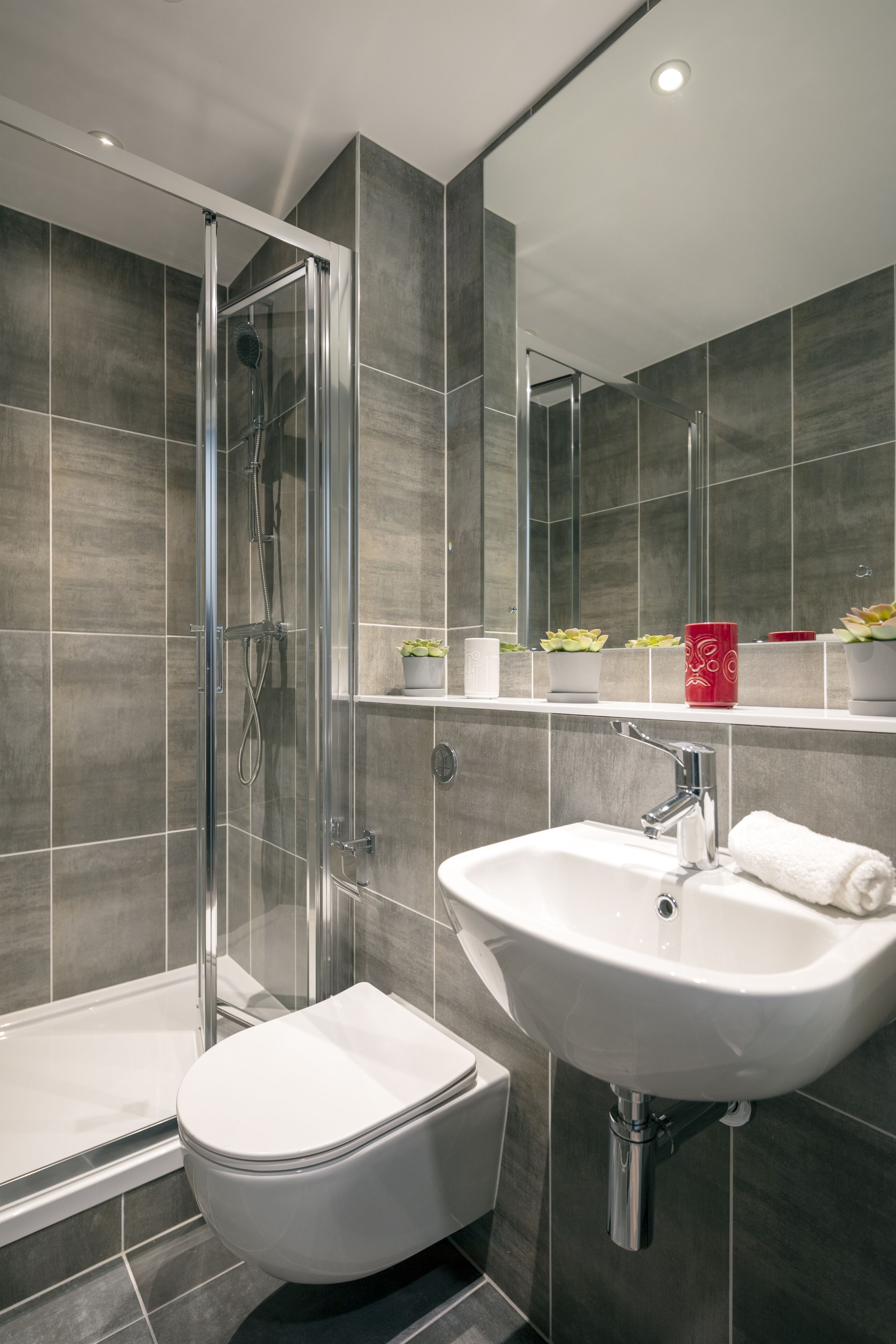 A modern bathroom with a glass-enclosed shower, a white sink, and a toilet.