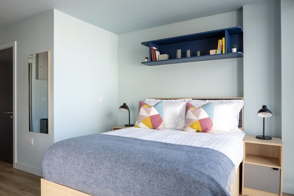 A bedroom with a bed, bedside tables, a mirror, and a bookshelf. - Coleman Court Summer Accommodation (Cork)