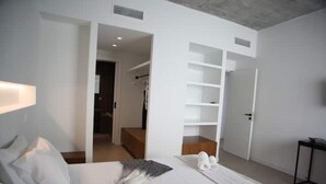 A modern hotel room with a neatly made bed, a walk-in closet, and a view into the hallway. - Athens Market Iconic Loft, Stunning Acropolis View (Athens)