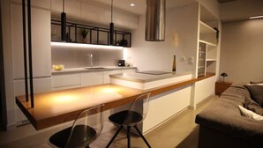 A modern kitchen with a central island, bar stools, and a built-in oven. - Athens Market Iconic Loft, Stunning Acropolis View (Athens)