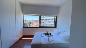 A bedroom with a bed, a window with a city view, and a tray with items on the bed. - Athens Market Iconic Apartment, Amazing view of the Acropolis (Athens)