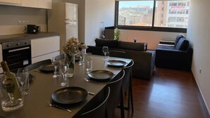 A modern kitchen with a dining area set for a meal, a sofa, and a view of the city through large windows. - Athens Market Iconic Apartment, Amazing view of the Acropolis (Athens)